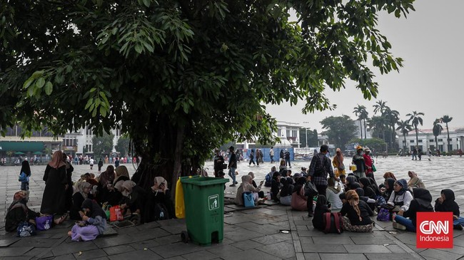 Sejumlah wisatawan membawa payung saat mengunjungi Kota Tua, Jakarta Barat, Sabtu (30/5/2025) siang.