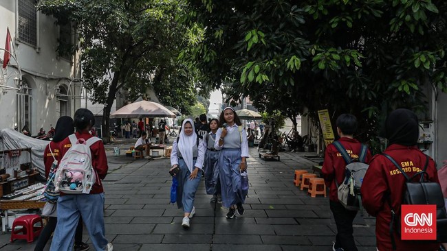 Sejumlah wisatawan membawa payung saat mengunjungi Kota Tua, Jakarta Barat, Sabtu (30/5/2025) siang. (CNN Indonesia/Febria Adha L)