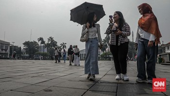Sejumlah wisatawan membawa payung saat mengunjungi Kota Tua, Jakarta Barat, Sabtu (30/5/2025) siang. (CNN Indonesia/Febria Adha L)