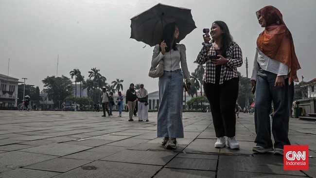 Sejumlah wisatawan membawa payung saat mengunjungi Kota Tua, Jakarta Barat, Sabtu (30/5/2025) siang. (CNN Indonesia/Febria Adha L)
