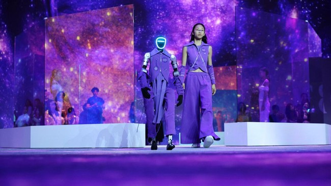 Robot dan model berjalan di atas catwalk dengan mengenakan busana serasi di Seoul.
