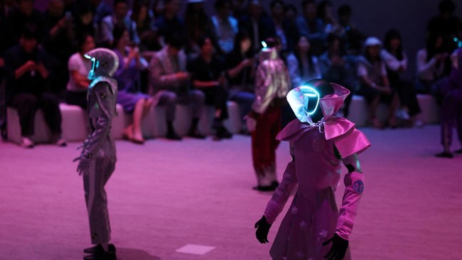 Robot dan model berjalan di atas catwalk dengan mengenakan busana serasi di Seoul.