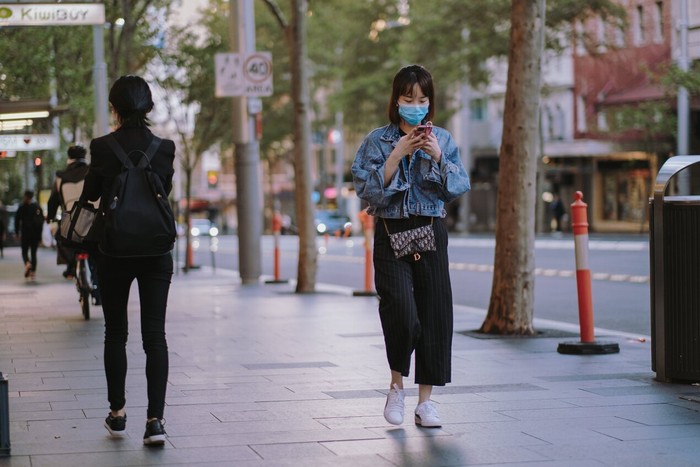Perempuan berjalan di trotoar sambil mengirim pesan/ Foto: Pexels.com/Kate Trifo
