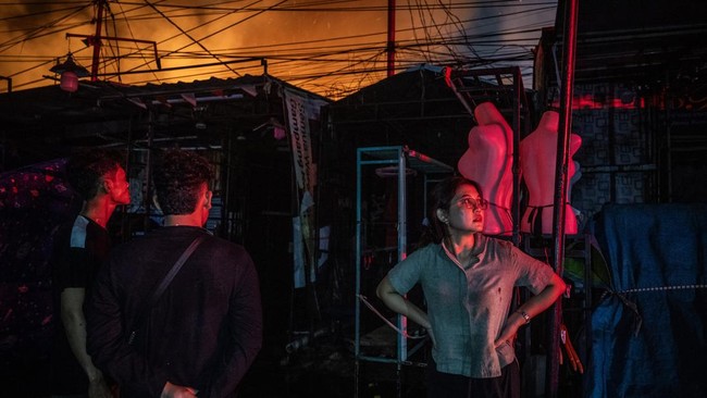 Warga berjaga di dekat kios saat terjadi kebarakan di Jalan Kemayoran Gempol, Kebon Kosong, Kemayoran, Jakarta, Senin (1/6/2026). Sebanyak 33 unit mobil pemadam kebakaran beserta 100 personel dikerahkan untuk menangani kebakaran yang melanda permukim