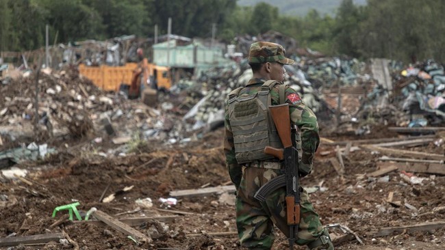 A member of the Ta'ang National Liberation Army (TNLA) stands guard next to the debris of buildings destroyed by an explosion in Kaung Tat village, in Namhkam Township in Myanmar's Shan state on June 2, 2026. A blast in northern Myanmar killed dozens