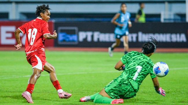 Pesepak bola Timnas Putri Indonesia Marsela Yuliana Awi (kiri) berusaha melewati penjaga gawang Timnas Putri Singapura putri Nur Izairida Shakira (kanan) saat bertanding pada ajang Garuda Championship Series di Stadion Arcamanik, Bandung, Jawa Barat,