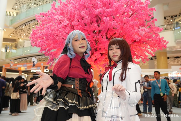 Selanjutnya ada perpaduan gaya classic Gothic Lolita dengan gaun megah perpaduan merah marun, hitam, dan aksen renda. Sementara itu, cosplayer kanan bergaya seragam sekolah.