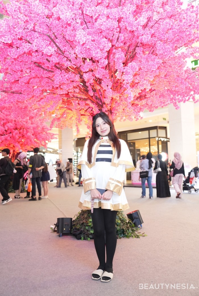 Di balik penampilan minimalis, cosplayer ini ternyata mengikuti gaya penyihir elf, Frieren dari serial&nbsp;Sousou no Frieren. Outfit-nya didominasi dengan warna putih,&nbsp;garis-garis hitam-putih di bagian dada, serta aksen emas di tepian jubah. Ia juga mengenakan stocking seperti karakter aslinya.