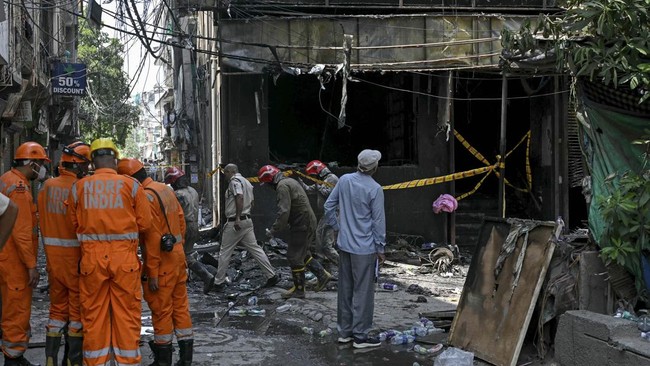National Disaster Response Force (NDRF) personnel and firefighters stand at the site following a fire that broke out at a hotel in New Delhi on June 3, 2026. At least 21 people were killed when a fire ripped through a hotel in New Delhi on June 3, po