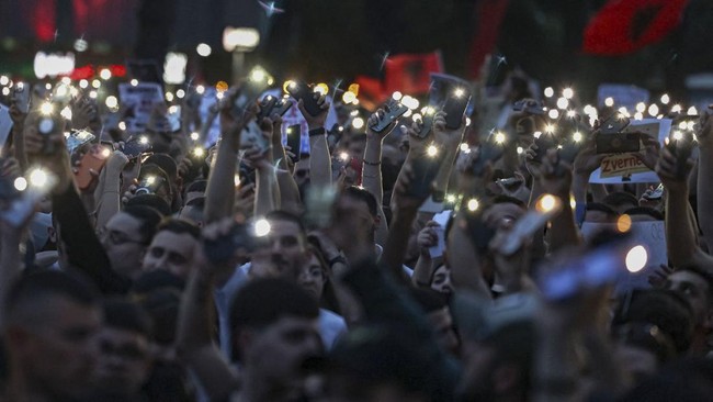 Protesters turn on their phone's lights during a protest against a luxury resort development planned by a company linked with Donald Trump's son-in-law, Jared Kushner, on an environmentally sensitive part of the Adriatic coast, in Tirana, Albania, Ju