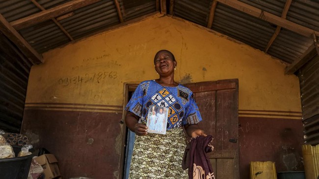Aduke Balogun, whose daughter was among dozens of pupils and teachers abducted in a large-scale school attack in southwestern Nigeria, reacts while displaying her daughter's photograph and clothing after an interview with Reuters at her home in Yawot