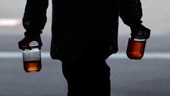 A resident brings used cooking oil to a waste oil collection point for the 'Fry to Fly' project, which collects used cooking oil from households to refine it into Sustainable Aviation Fuel (SAF), at a community center in Adachi Ward, Tokyo, Japan, Ap