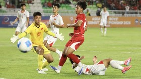 Pesepak bola Timnas Indonesia U-19  Fabio Azkairawan (tengah) mencoba menaklukkan penjaga gawang Vietnam U-19 Xuan Tin Hoa (kiri).
