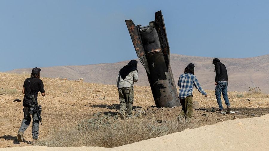 Para pemukim Israel berdiri di samping bagian rudal nan mencuat dari tanah, setelah serangan dari Iran, di Tepi Barat bagian tengah nan diduduki Israel, 8 Juni 2026.