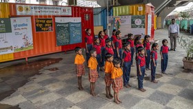 This photograph taken on May 18, 2026 shows children singing the national anthem at the "Signal Shala", or traffic signal school, under a bridge in Mumbai. Beneath a busy flyover in India's financial capital Mumbai, a row of pastel-coloured shipping