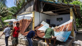 People collect their belongins from a damaged house following an earthquake off the southern Philippine island of Mindanao.