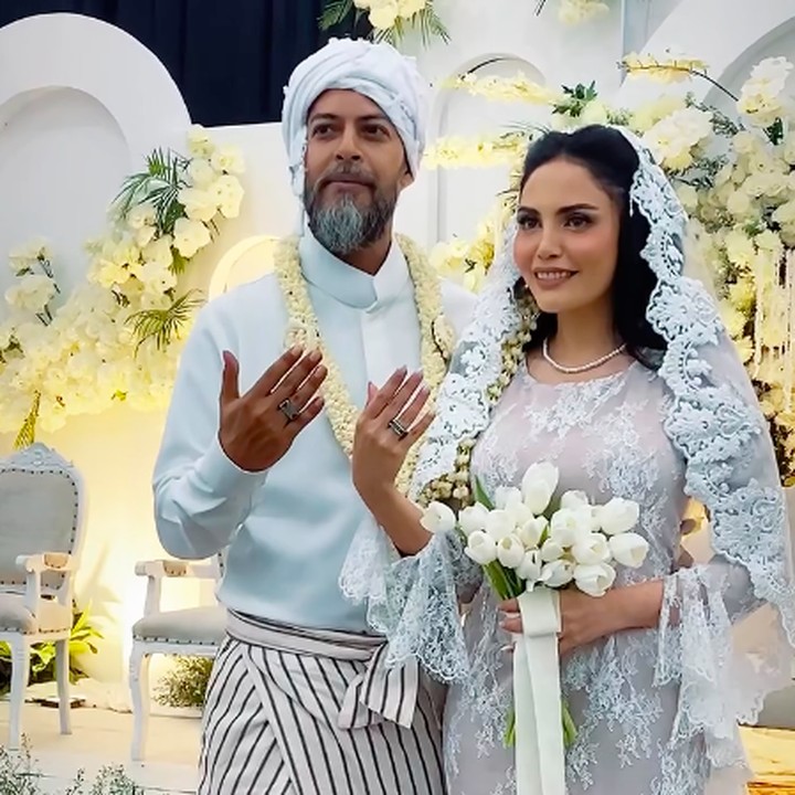 <p>Di acara akad nikah ini, Alex dan Nadya menggunakan pakaian bernuansa warna putih. Alex terlihat mengenakann celana kain motif garis-garis dan penutup kepala putih. Sementara itu, Nadya tampil cantik memakai kebaya pernikahan dann aksesoris kerudung putih. (Foto: Instagram @baimguitar)</p>