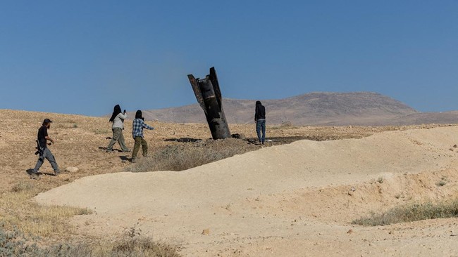 Israeli settlers stand next to part of a missile protruding from the ground, following strikes from Iran, in the central Israeli-occupied West Bank, June 8, 2026. REUTERS/Naama Stern ISRAEL OUT. NO COMMERCIAL OR EDITORIAL SALES IN ISRAEL