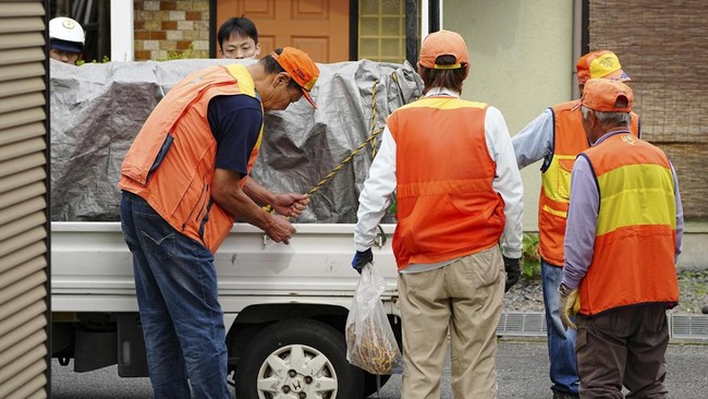 Hunters stand next to a truck carrying a sedated wild bear after it was captured in Utsunomiya, north of Tokyo, on June 9, 2026. A bear roaming the streets of a Japanese city for days forced the closure of nearly 100 schools, as dozens of hunters and