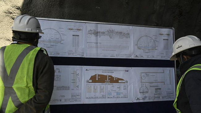 Engineers looks at a plan of the Zojila tunnel under construction which connects Srinagar to the union territory of Ladakh, at Baltal, some 93 km northeast of Srinagar, on September 28, 2021. (Photo by TAUSEEF MUSTAFA / AFP)