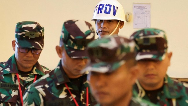A military police officer escorts Indonesian military personnel Sami Lakka, Nandala Dwi Prasetya, Budhi Hariyanto Widhi Cahyono, and Edi Sudarko, charged over an acid attack on human rights activist Andrie Yunus, a ‌deputy coordinator with the righ