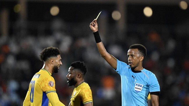 (FILES) Gabon's forward #20 Denis Bouanga is shown the yellow card by Somali referee Omar Abdulkadir Artan during the Africa Cup of Nations (CAN) Group F football match between Gabon and Ivory Coast at the Grand Stadium in Marrakech on December 31, 2