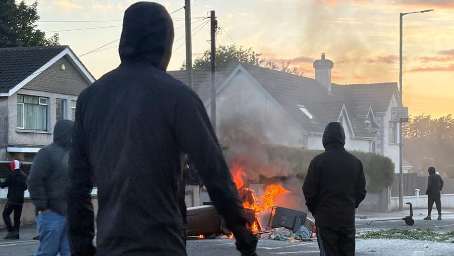 Api berkobar di tempat sampah saat demonstran anti-imigran berantem dengan polisi di jalan Antrim, menyusul serangan pisau pada 8 Juni nan menyebabkan seorang laki-laki terluka parah dan mendorong polisi untuk menyatakan kejadian kritis, di Belfast, Irlandia Utara, 10 Juni 2026.