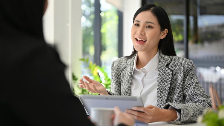 Attractive beautiful young Asian businesswoman or female marketing employee presenting her project&comma; sharing her marketing ideas to her coworker while working together ib the office&period;