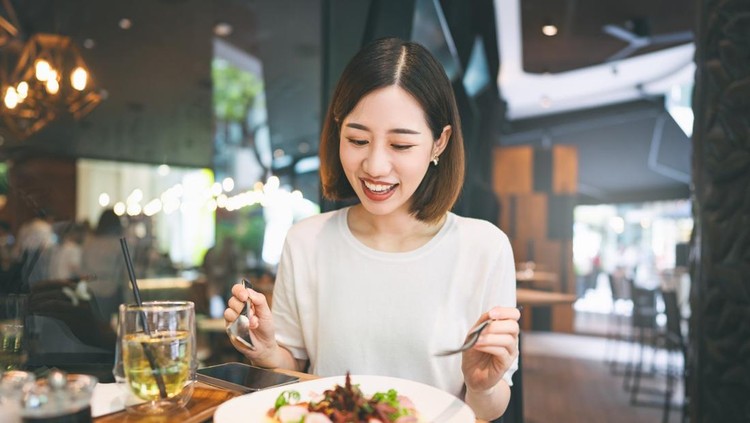 Weekend city break people lifestyle concept&period; Young adult asian woman eating healthy food diet meal&period; At indoors cafe restaurant on day&period; Happy smile face and short hair person&period;