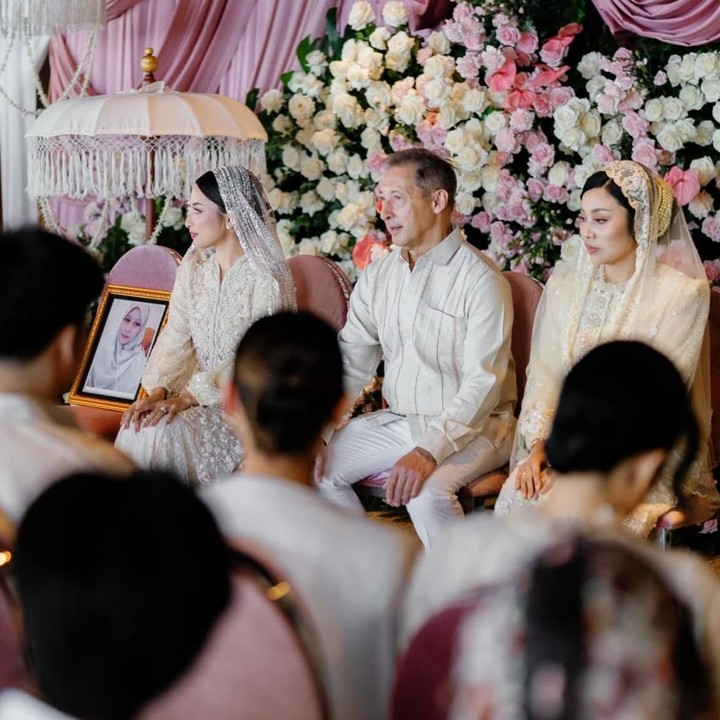 <p>Pada momen bahagia ini, Jennifer tampak duduk di kursi, sementara di sampingnya terdapat sebuah kursi dengan foto berbingkai mendiang sang ibunda, Hotimah Imaniar. Foto tersebut seolah jadi simbol kehadiran almarhumah ibunda dalam momen sakral itu. (Foto: @fcgweddings via Instagram @jennifercoppenreal20)</p>
