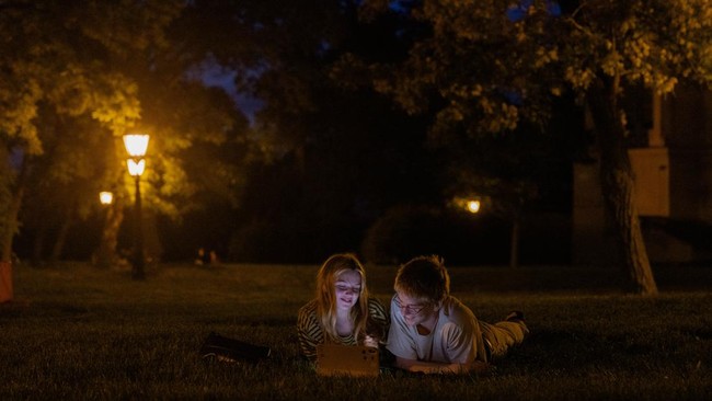 teenagers lay on the grass in the evening in Kyiv on June 5, 2026, amid the Russian invasion of Ukraine. (Photo by Tetiana DZHAFAROVA / AFP)