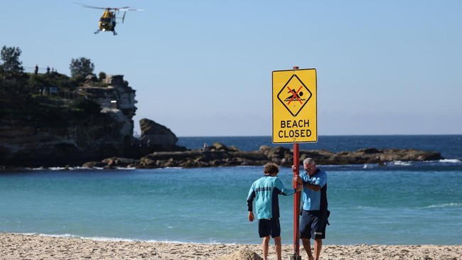 Lifeguards erect a sign that says