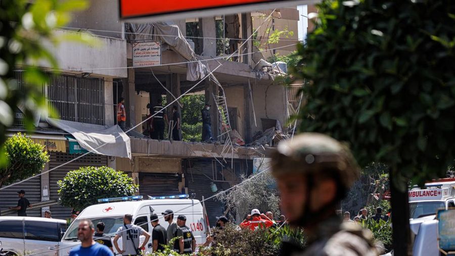 Seorang perwira tentara Lebanon berdiri sementara petugas polisi dan personel darurat bekerja di letak serangan Israel di pinggiran selatan Beirut, Lebanon, 14 Juni 2026.