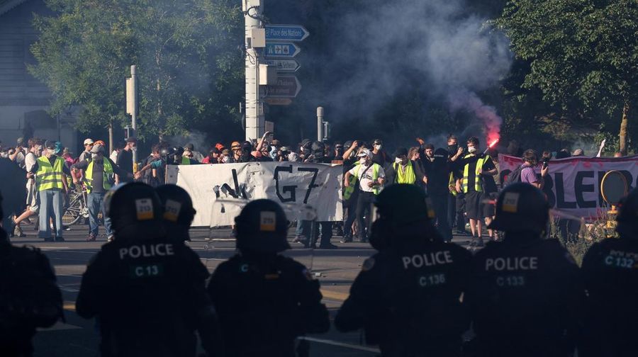 Polisi anti huru hara berhati-hati sementara para demonstran memegang spanduk dan suar selama protes menentang KTT G7 nan bakal datang di Evian-les-Bains di Prancis, di Jenewa, Swiss, 14 Juni 2026.