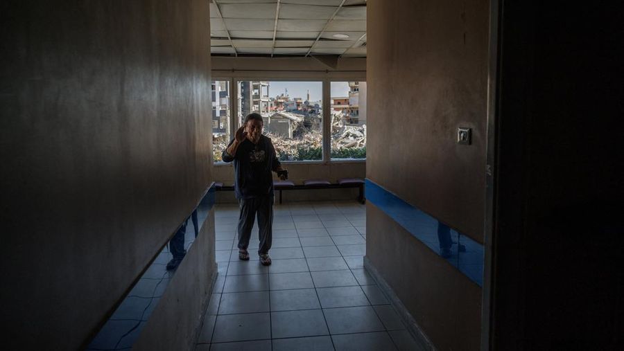 Youssef Fares, 90, whose home of more than 70 years, was reportedly damaged by an Israeli airstrike, waves as he walks near broken windows of Jabal Amel hospital where he has taken shelter with his family, overlooking buildings damaged by Israeli str