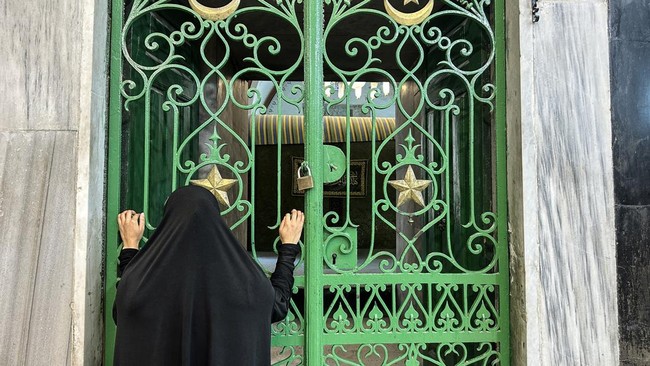 A woman looks through an iron gate during celebrations of the Islamic Hijri New Year at the Ibrahimi Mosque, known to Jews as the Cave of the Patriarchs, located inside the Israeli-controlled H2 sector of the occupied West Bank city of Hebron, on Jun