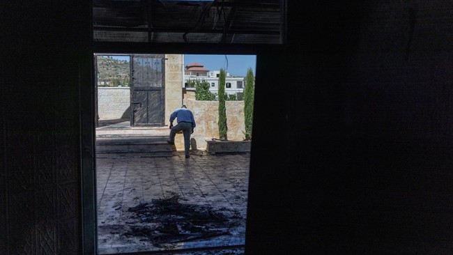 A Palestinian man rinses the soles of his shoes from soot after inspecting the damage inside a mosque reportedly burnt by Israeli settlers over night, in the Israeli occupied West Bank village of Jiljlia, just north of the West Bank city of Ramallah