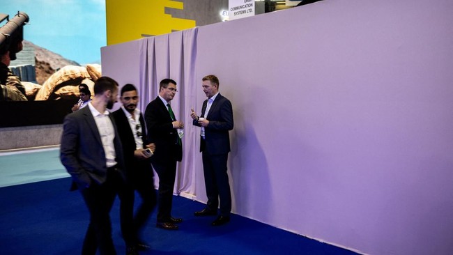 Visitors walk by the closed stand of Israeli airborne and maritime communications, satellite tracking, and ground-station technology company Orbit Communication Systems at the Eurosatory land and airland defence and security trade fair, at the Paris-