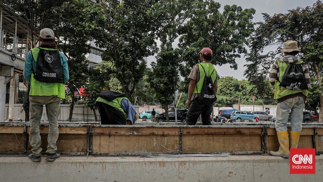 Sejumlah pekerja memugarkan area pedestrian Rasuna Said dalam rangka menyambut HUT DKI Jakarta ke-499 di Kuningan, Jakarta, Rabu (17/6). (CNN Indonesia/Febria Adha L)