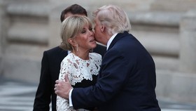 France's President Emmanuel Macron (L) and his wife Brigitte Macron (C) welcome US President Donald Trump (R) at Chateau de Versailles ahead of a dinner to celebrate the 250th anniversary of the independence of the United States, in Versailles southw