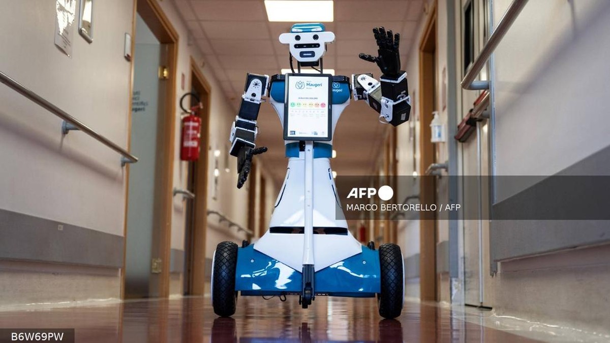 Sebuah robot humanoid setinggi 120 sentimeter berjalan pelan menyusuri koridor rumah sakit, mendekati pasien di kursi roda, lalu memulai percakapan.