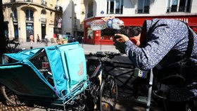 A Deliveroo delivery worker cools his head with a bottle of water next to his bike as a heatwave hits a large part of France, June 18, 2026. REUTERS/Abdul Saboor