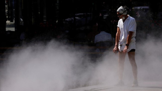 A man cools off in a water mister on the Place de la Republique in Paris as a heatwave hits a large part of France, June 18, 2026. REUTERS/Alice Sacco