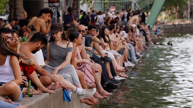 People sit along the Canal Saint-Martin to find some relief from the heat as public swimming having been allowed earlier on part of it due to rising of temperatures, in Paris as a heatwave hits a large of France, June 18, 2026. REUTERS/Alice Sacco