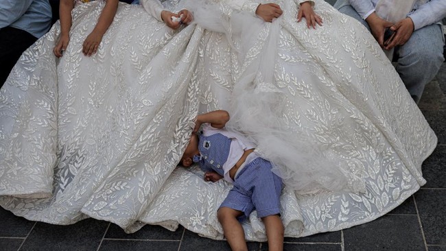 A boy lies on part of the white dress of the bride, Zainab Khawaja, 20, who is displaced from the village of Haris in southern Lebanon, as she celebrates her marriage to Lebanese groom Hassan Jawad, 22, who lives in Burkina Faso and is originally fro