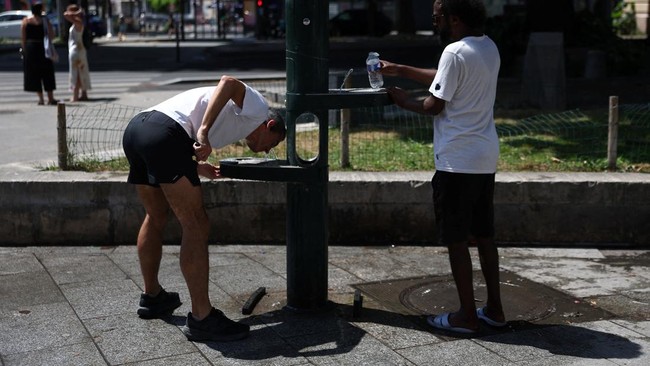 People drink water at a fountain on a street in Paris as temperatures rise during a heatwave affecting a large part of France, June 22, 2026. REUTERS/Alice Sacco