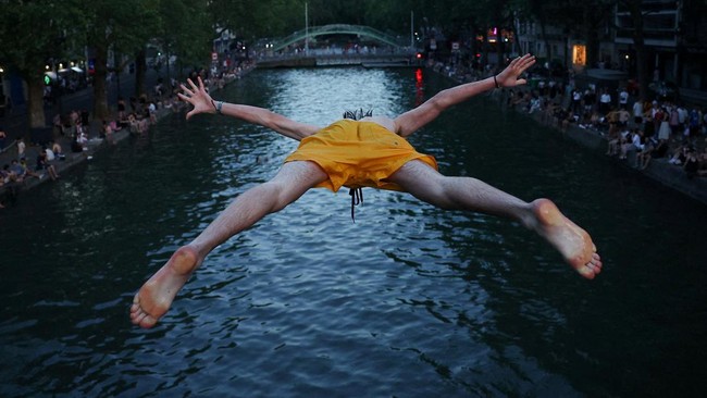 A man dives into the water in the Canal Saint-Martin as temperatures rise during a heatwave affecting a large part of the country, in Paris, France, June 22, 2026. REUTERS/Abdul Saboor      TPX IMAGES OF THE DAY