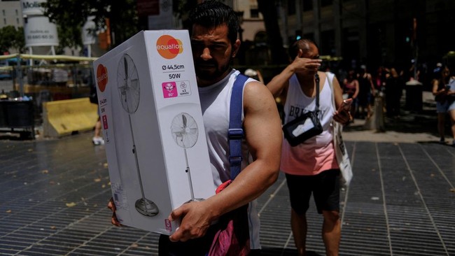 A man carries a newly purchased fan as temperatures rise, during a heatwave affecting a large part of Spain, in Barcelona, in Spain, June 21, 2026. REUTERS/Nacho Doce