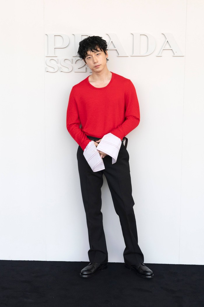Warna merah pada sweater bukan cuma satu-satunya daya tarik penampilan aktor Jepang, Kentaro Sakaguchi. Lengan kemeja bergaris yang oversized memberi sentuhan dramatis pada keseluruhan look minimalisnya/ Foto: Dok. Prada