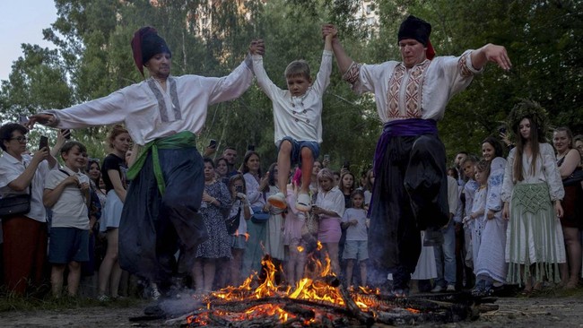 People jump over a bonfire during Ivana Kupala celebrations, an ancient tradition rooted in pagan rites that is marking summer solstice, amid Russia's attack on Ukraine, at the Mamayeva Sloboda outdoor museum in Kyiv, Ukraine June 23, 2026.  REUTERS/